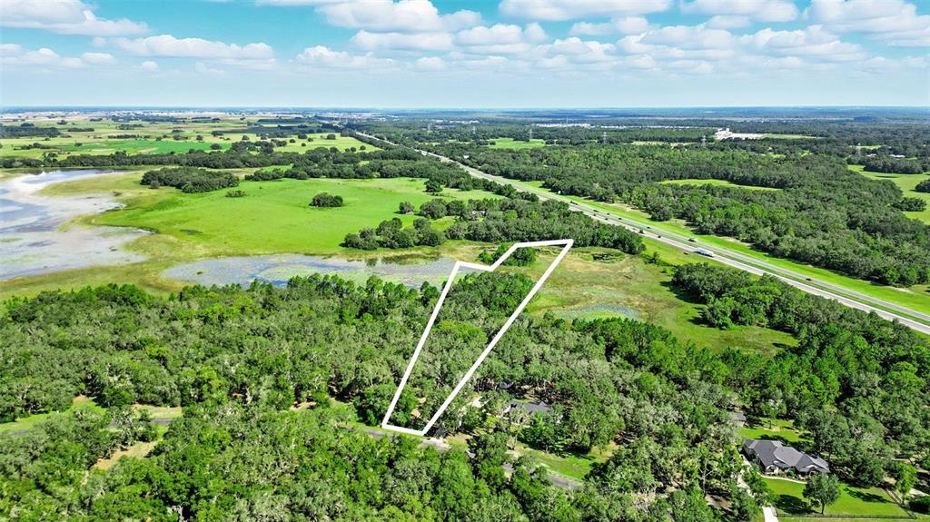 An aerial view shows a wooded plot of land outlined in white near a highway — 3155 BRIGHT LAKE CIRCLE, GROVELAND, FL