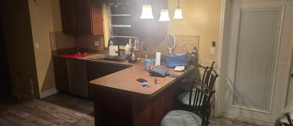 A kitchen features dark wood cabinets, a breakfast bar, and a tiled backsplash — 4906 PRESIDENTIAL STREET, SEFFNER, FL