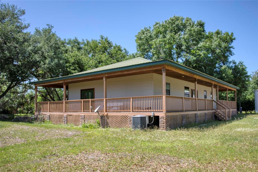 A single-story house with a wrap-around wooden deck and a green metal roof — 5525 MITCHELL BRIDGES ROAD, CLERMONT, FL
