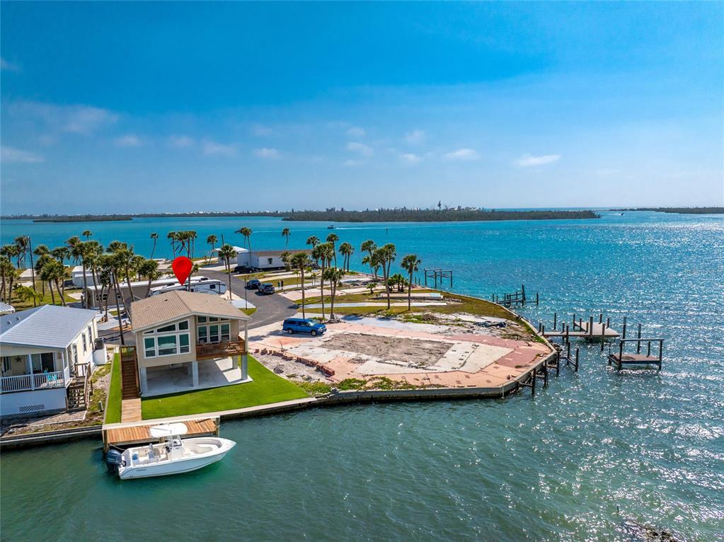 An aerial view shows a waterfront house with a boat dock and a vacant lot — 7500 PARK POINTE DRIVE UNIT 42, ENGLEWOOD, FL