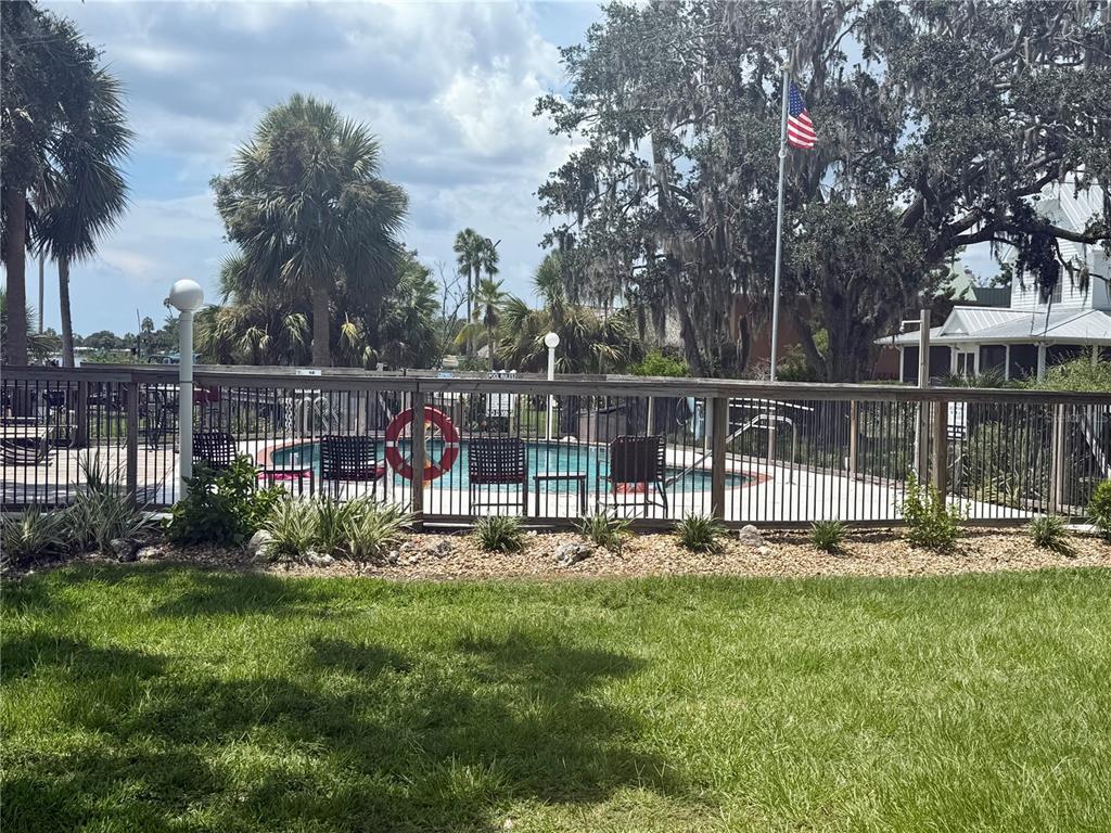 A fenced swimming pool area features patio furniture, a life ring, and surrounding trees — 5111 S GRAY PELICAN WAY UNIT 5111, HOMOSASSA, FL