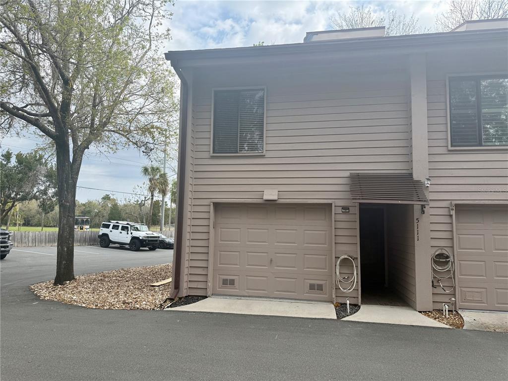 A two-story townhouse exterior features a beige garage, a recessed entry, and a gravel landscape — 5111 S GRAY PELICAN WAY UNIT 5111, HOMOSASSA, FL