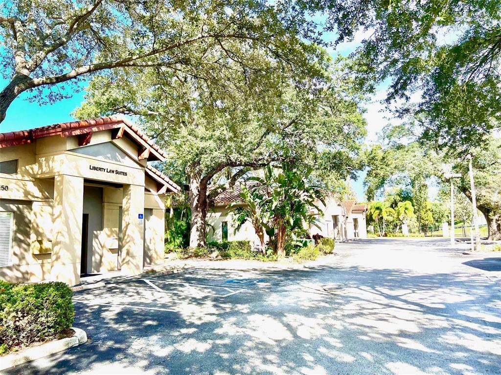 A tan commercial building with a tile roof sits in a parking lot with trees — 1550 W CLEVELAND STREET UNIT 2, TAMPA, FL