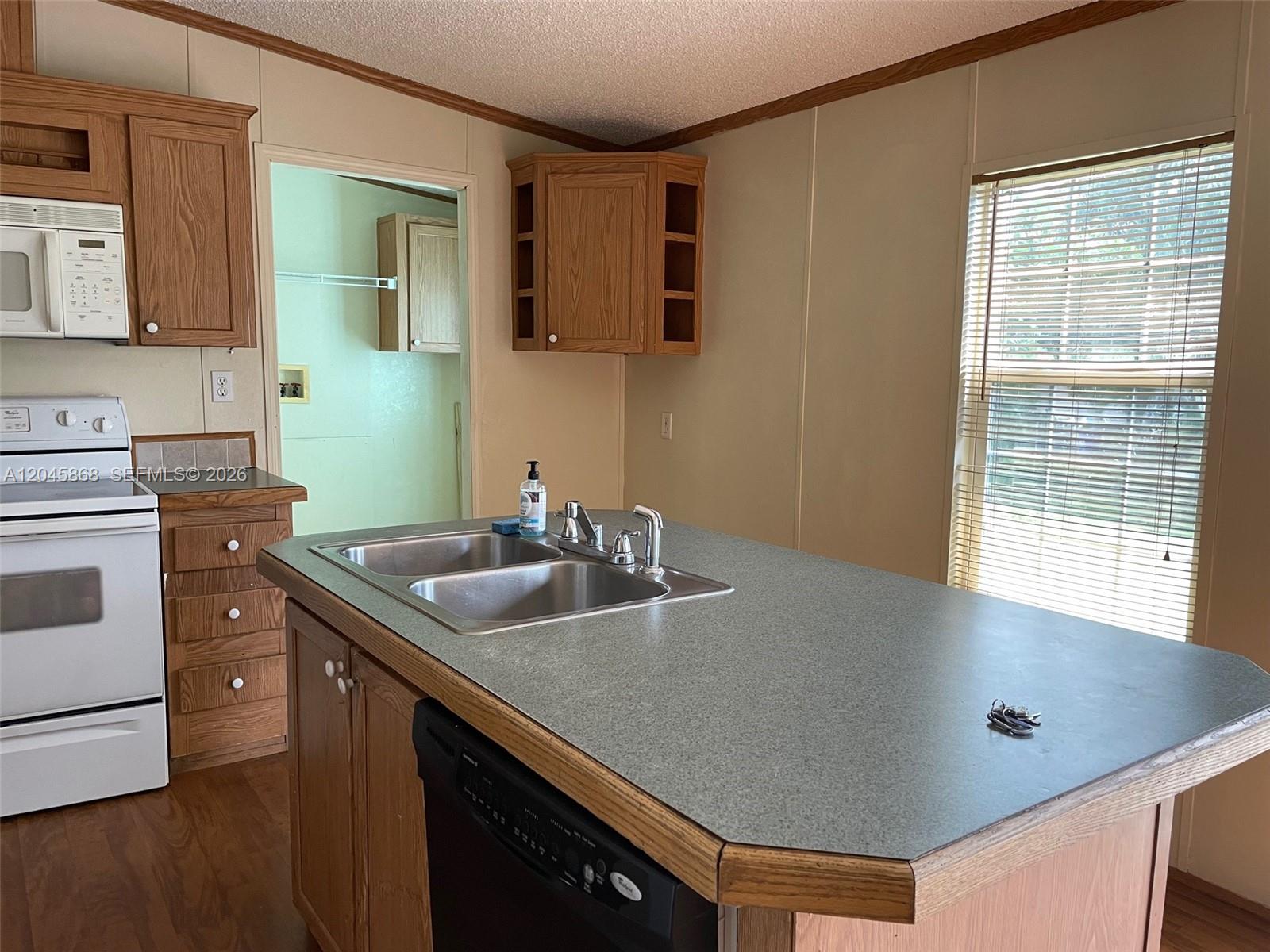 A kitchen features wood cabinets, a central island with a sink, and a white stove — 11864 Atlantic Cir # H, Boca Raton FL 33428, BOCA RATON, FL