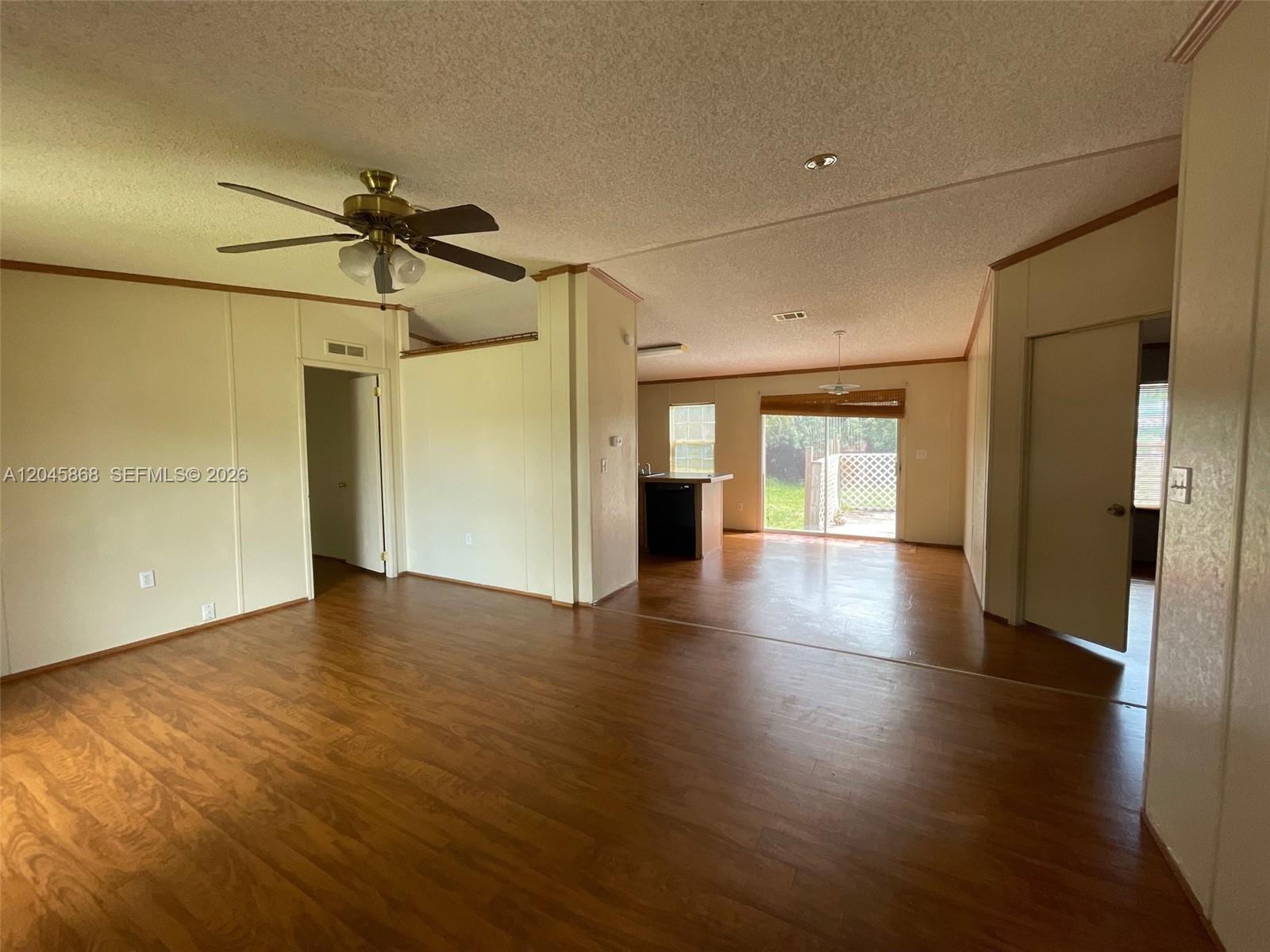 An open-concept living area features wood-look flooring, a ceiling fan, and a sliding glass door — 11864 Atlantic Cir # H, Boca Raton FL 33428, BOCA RATON, FL