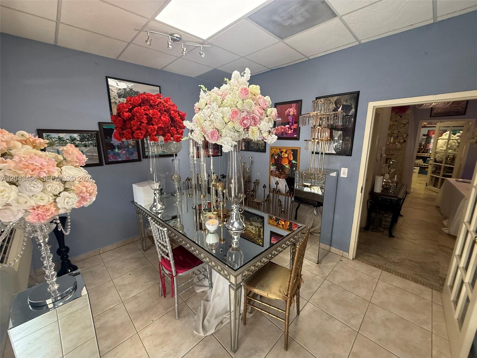 A room features a mirrored table with floral centerpieces, chairs, and framed wall art — 5921 NW 176th St # 9, Hialeah FL 33015, HIALEAH, FL