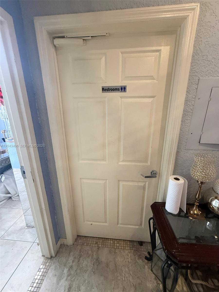 A white door labeled "Restrooms" is positioned next to a small table with paper towels — 5921 NW 176th St # 9, Hialeah FL 33015, HIALEAH, FL