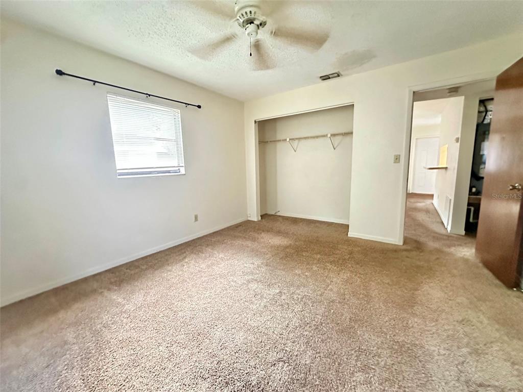 A bedroom features beige carpeting, a ceiling fan, a window with blinds, and a closet — 3635 135TH AVENUE UNIT C, LARGO, FL