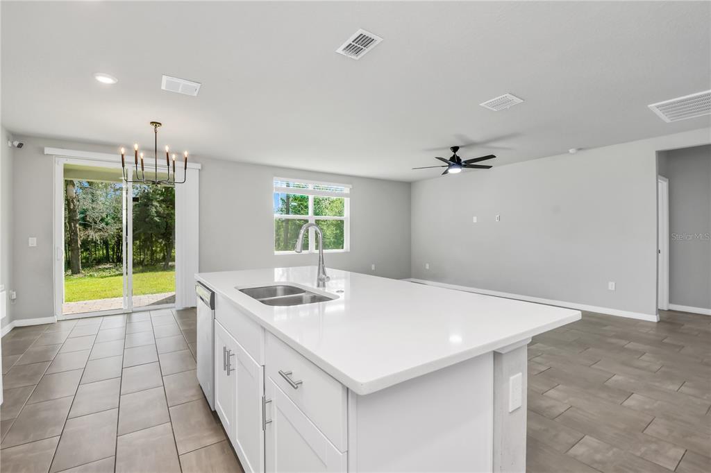 A kitchen island with a white countertop sits in an open-concept room with tile flooring — 17413 BACK BAY COURT, CLERMONT, FL