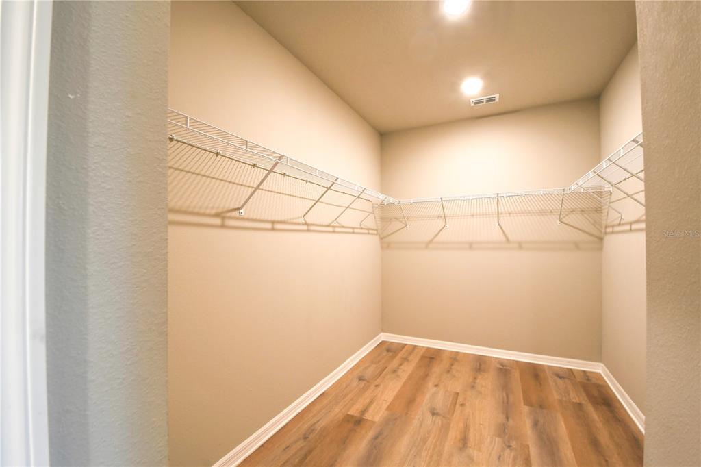 A walk-in closet features white wire shelving, light-colored walls, and wood-look flooring — 17413 BACK BAY COURT, CLERMONT, FL