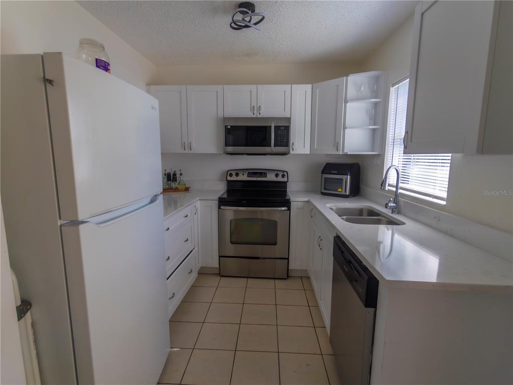 A hallway with tiled flooring, a white door, and a pass-through opening to another room — 4718 ELDORADO DRIVE, TAMPA, FL