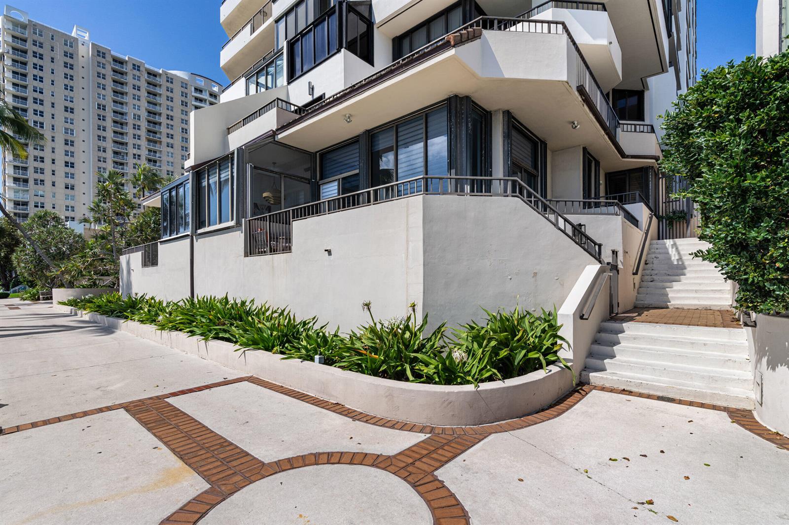 The exterior of a multi-story building features a concrete patio, stairs, and landscaped garden beds — 520 Brickell Key Drive # A200, Miami FL 33131, MIAMI, FL
