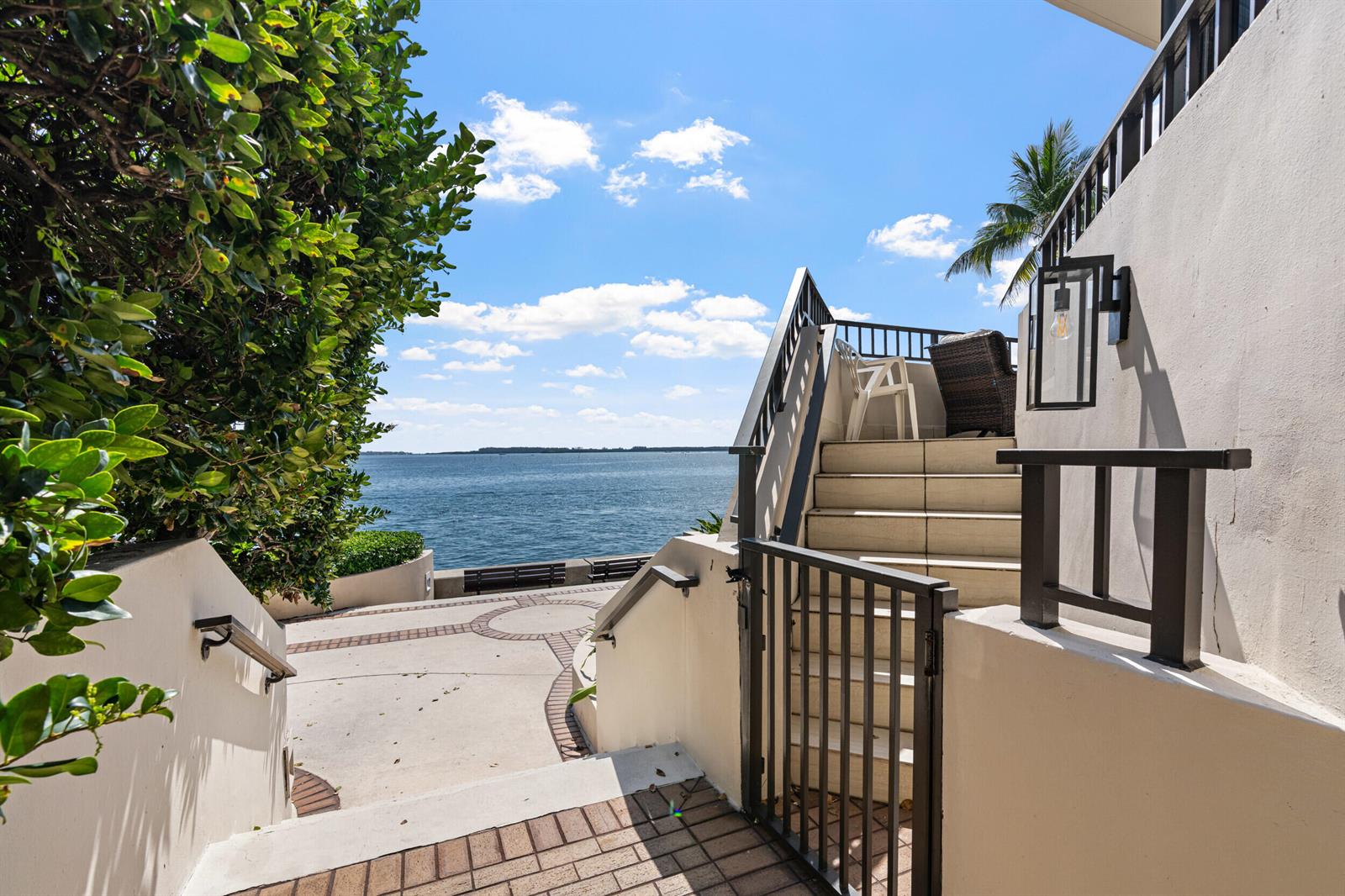 An outdoor staircase leads down to a paved patio overlooking a body of water — 520 Brickell Key Drive # A200, Miami FL 33131, MIAMI, FL