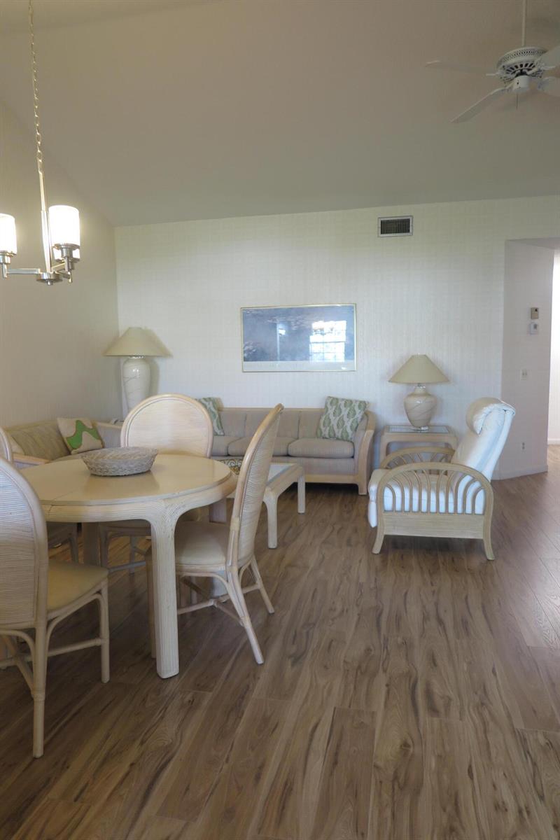 A dining area and living room featuring light wood furniture, beige sofas, and wood-look flooring — 6707 Via Regina, Boca Raton FL 33433, BOCA RATON, FL