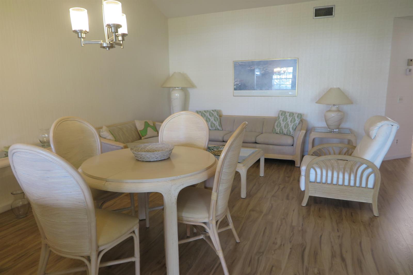 A dining area and living room feature light wood-look flooring and wicker furniture — 6707 Via Regina, Boca Raton FL 33433, BOCA RATON, FL