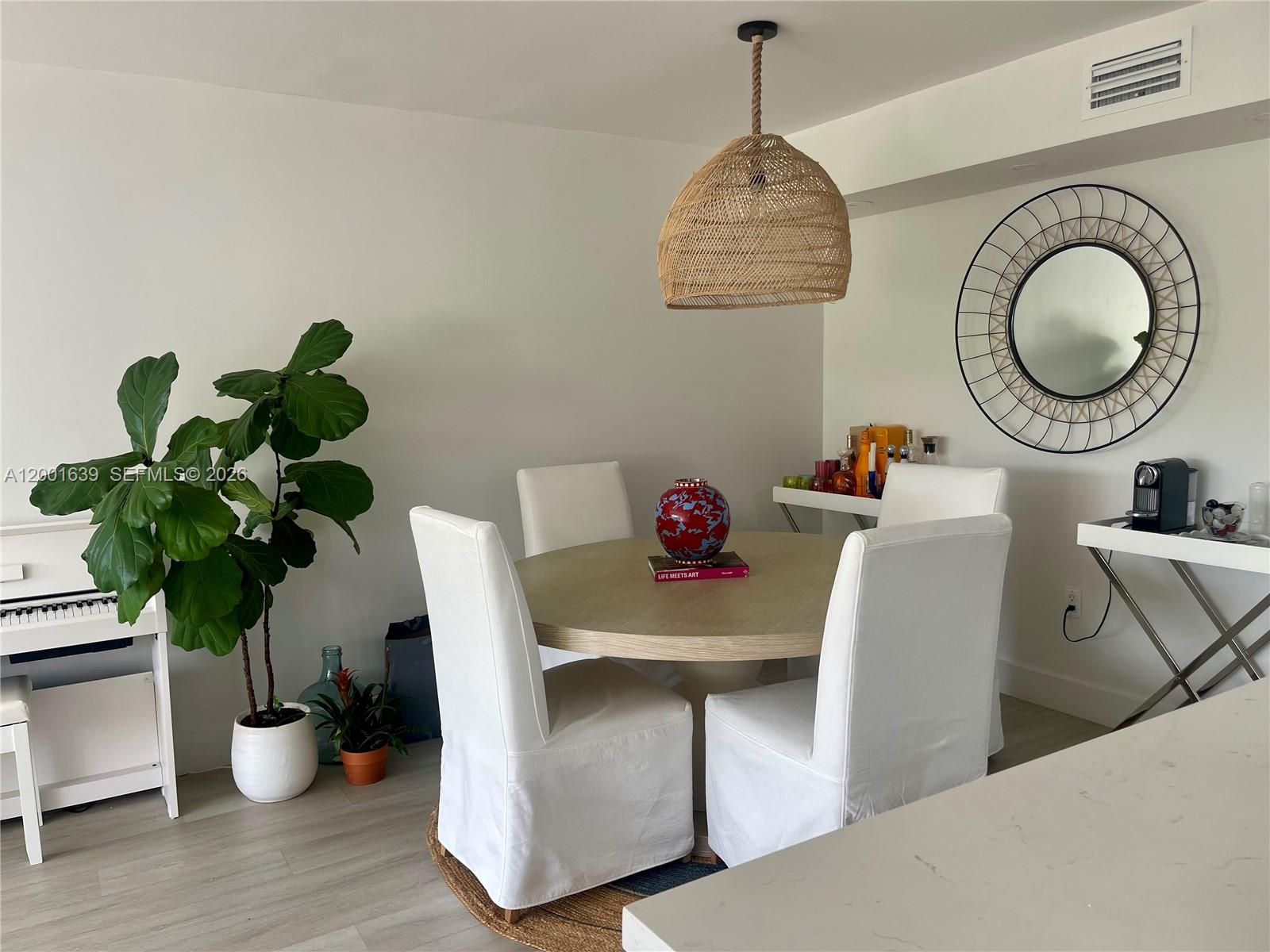 A dining area features a round wooden table, four white chairs, and a woven pendant light — 255 Galen Dr # 3D, Key Biscayne FL 33149, KEY BISCAYNE, FL