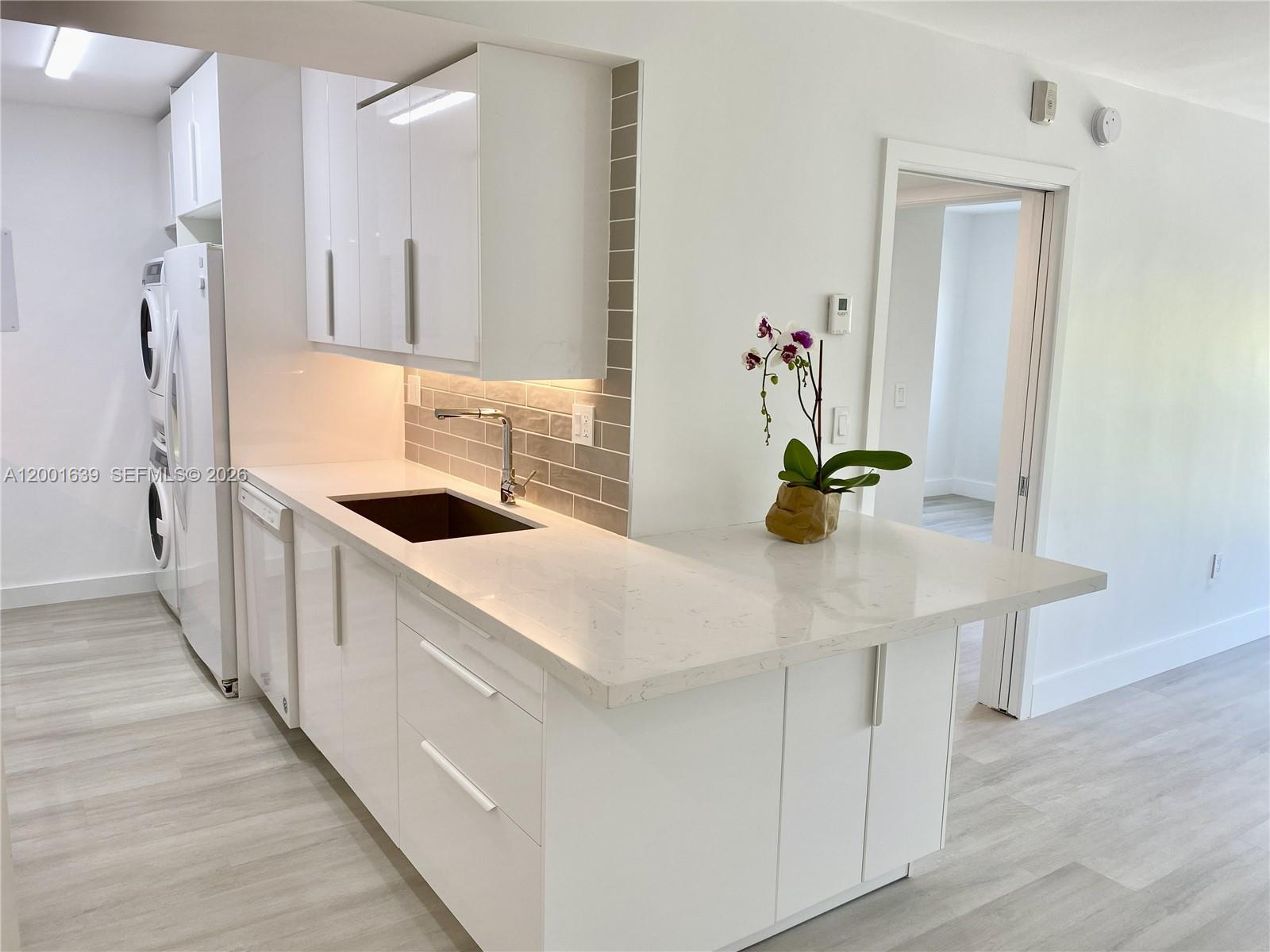 A modern kitchen features white cabinets, quartz countertops, a gray tile backsplash, and stainless appliances — 255 Galen Dr # 3D, Key Biscayne FL 33149, KEY BISCAYNE, FL