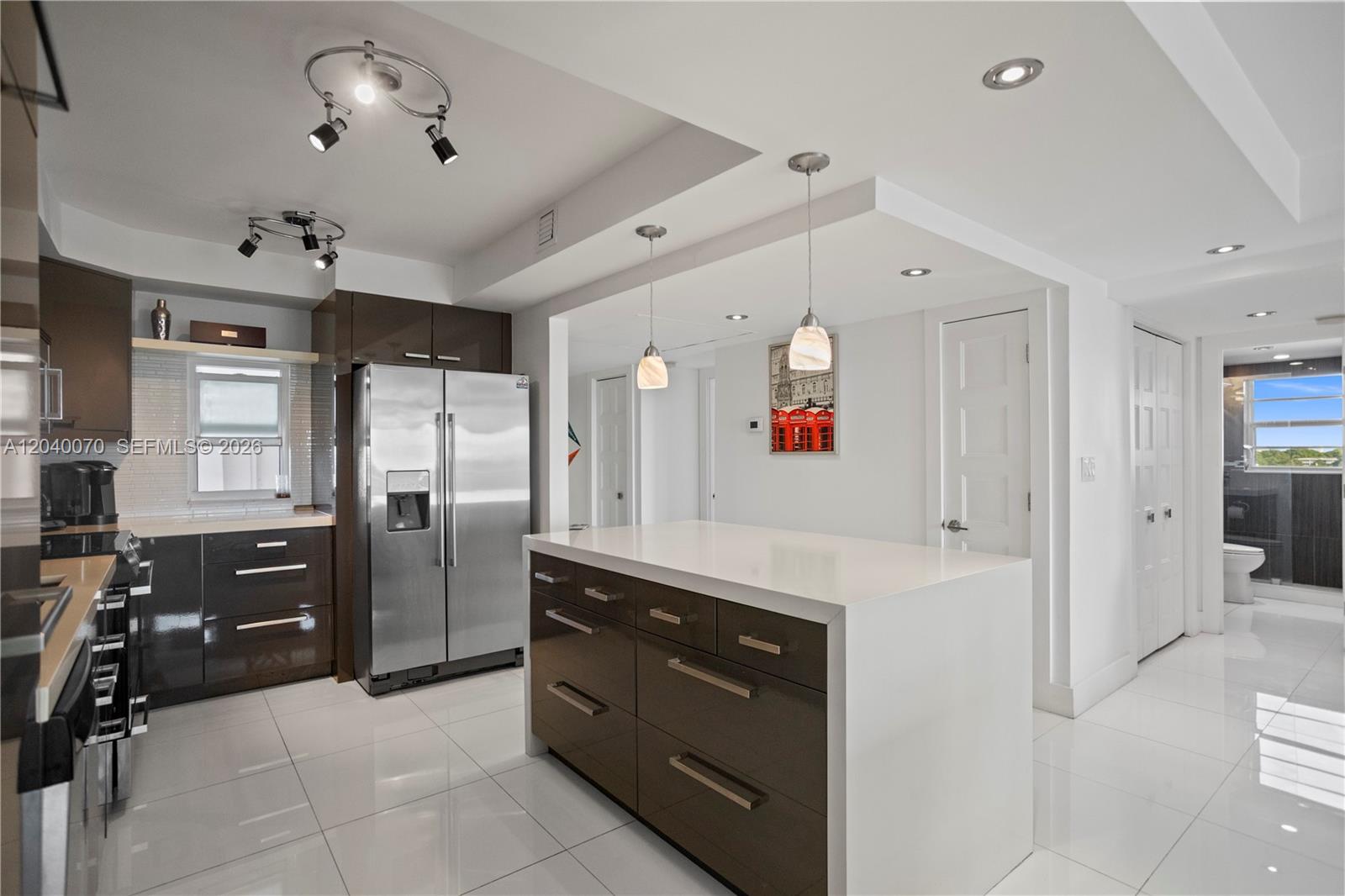 A modern kitchen features dark cabinetry, a white waterfall island, and stainless steel appliances — 3050 N Palm Aire Dr # 710, Pompano Beach FL 33069, POMPANO BEACH, FL