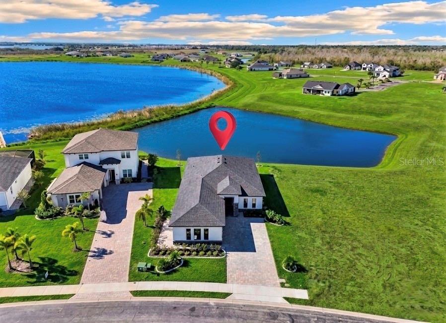 An aerial view of a modern single-story house with a paved driveway and waterfront backyard — 224 VALENCIA RIDGE DRIVE, AUBURNDALE, FL