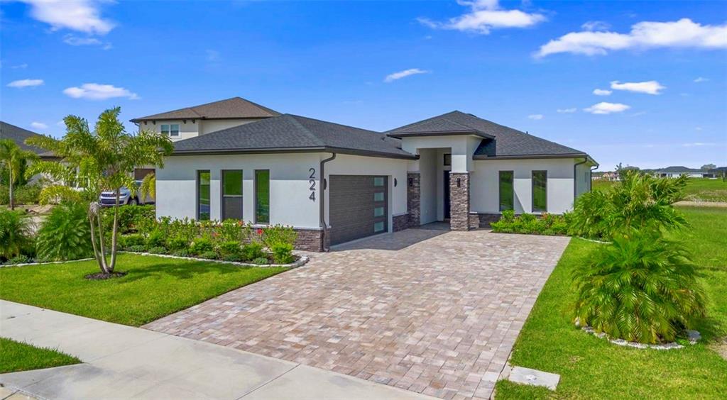 An aerial view of a modern single-story house with a paver driveway and waterfront backyard — 224 VALENCIA RIDGE DRIVE, AUBURNDALE, FL