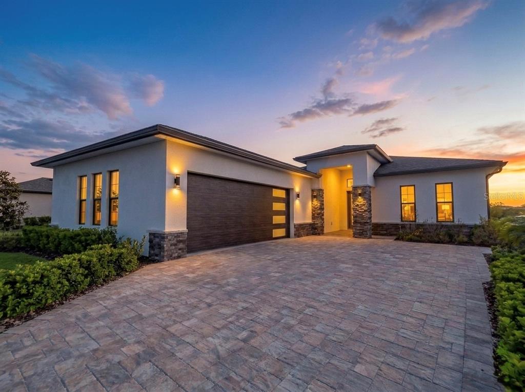 A modern single-story house with a paved driveway, stone accents, and a dark garage door — 224 VALENCIA RIDGE DRIVE, AUBURNDALE, FL