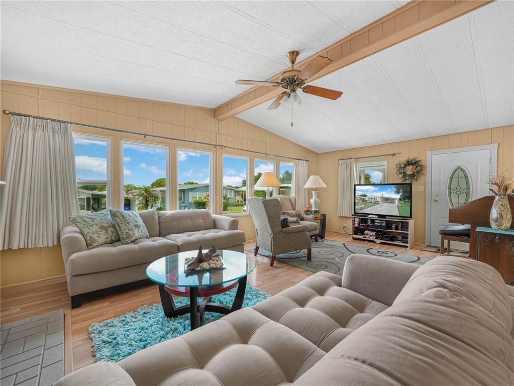 A living room features light wood flooring, tan walls, a ceiling fan, and two sofas — 1632 FOXWAY DRIVE, LAKELAND, FL