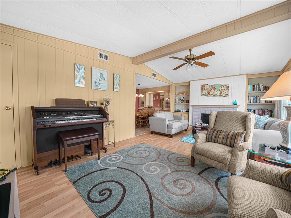 A living room features a piano, a fireplace, a ceiling fan, and a patterned rug — 1632 FOXWAY DRIVE, LAKELAND, FL