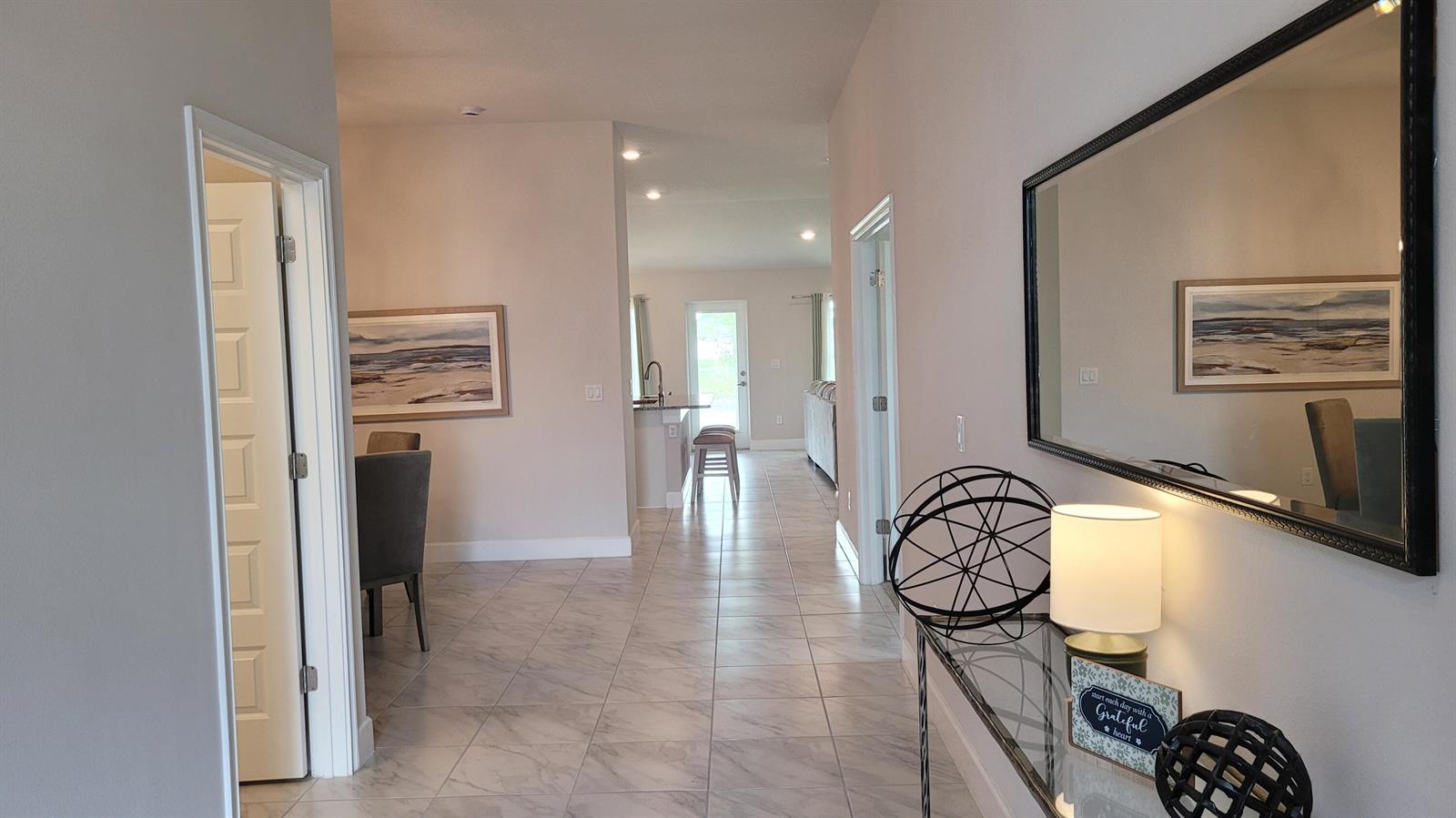 A hallway with tile flooring leads to an open kitchen and living area — 8820 Waterstone Boulevard, Fort Pierce FL 34951, FORT PIERCE, FL