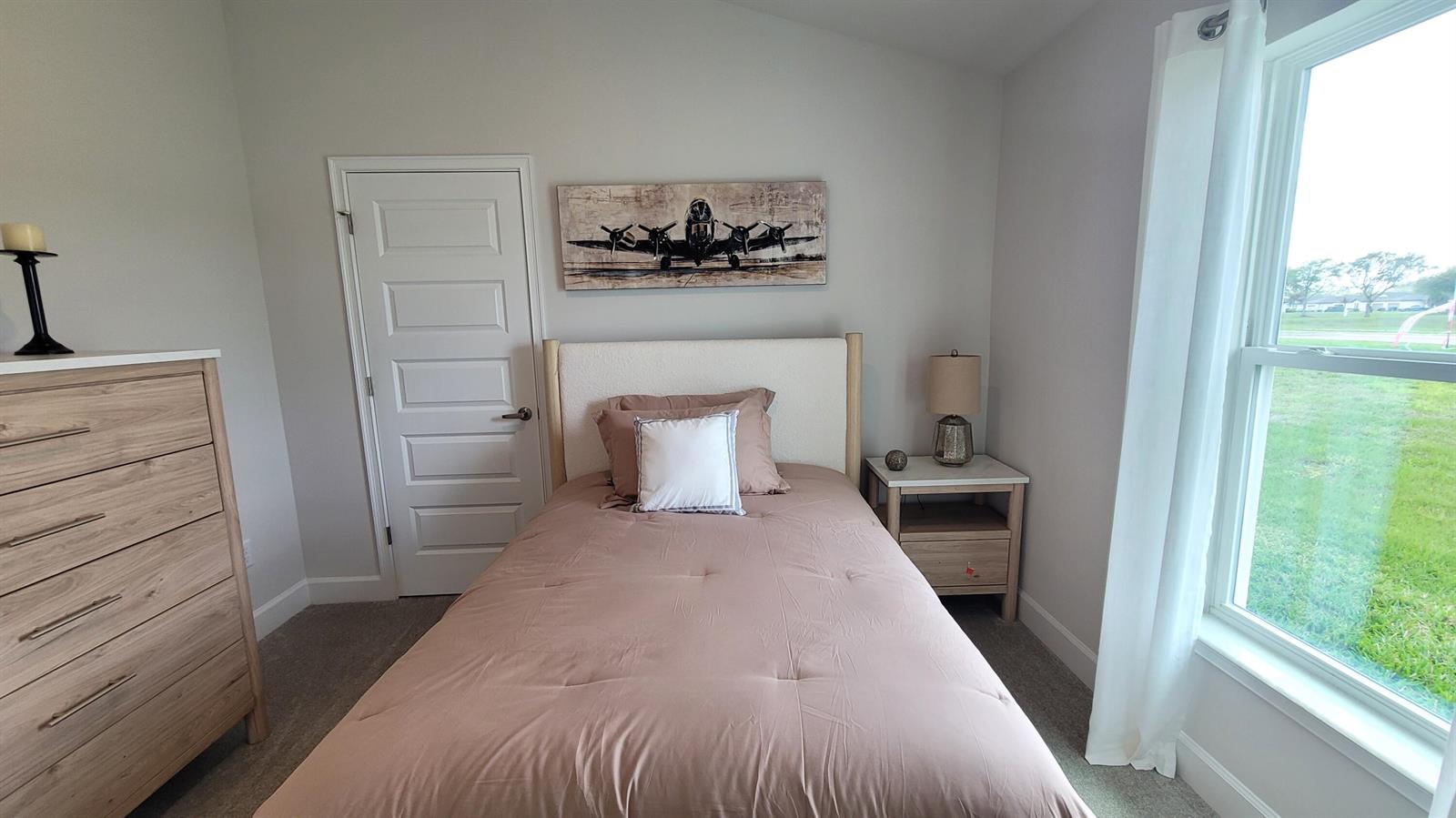 A bedroom features a bed with a tan comforter, a wooden dresser, and an airplane print — 8820 Waterstone Boulevard, Fort Pierce FL 34951, FORT PIERCE, FL