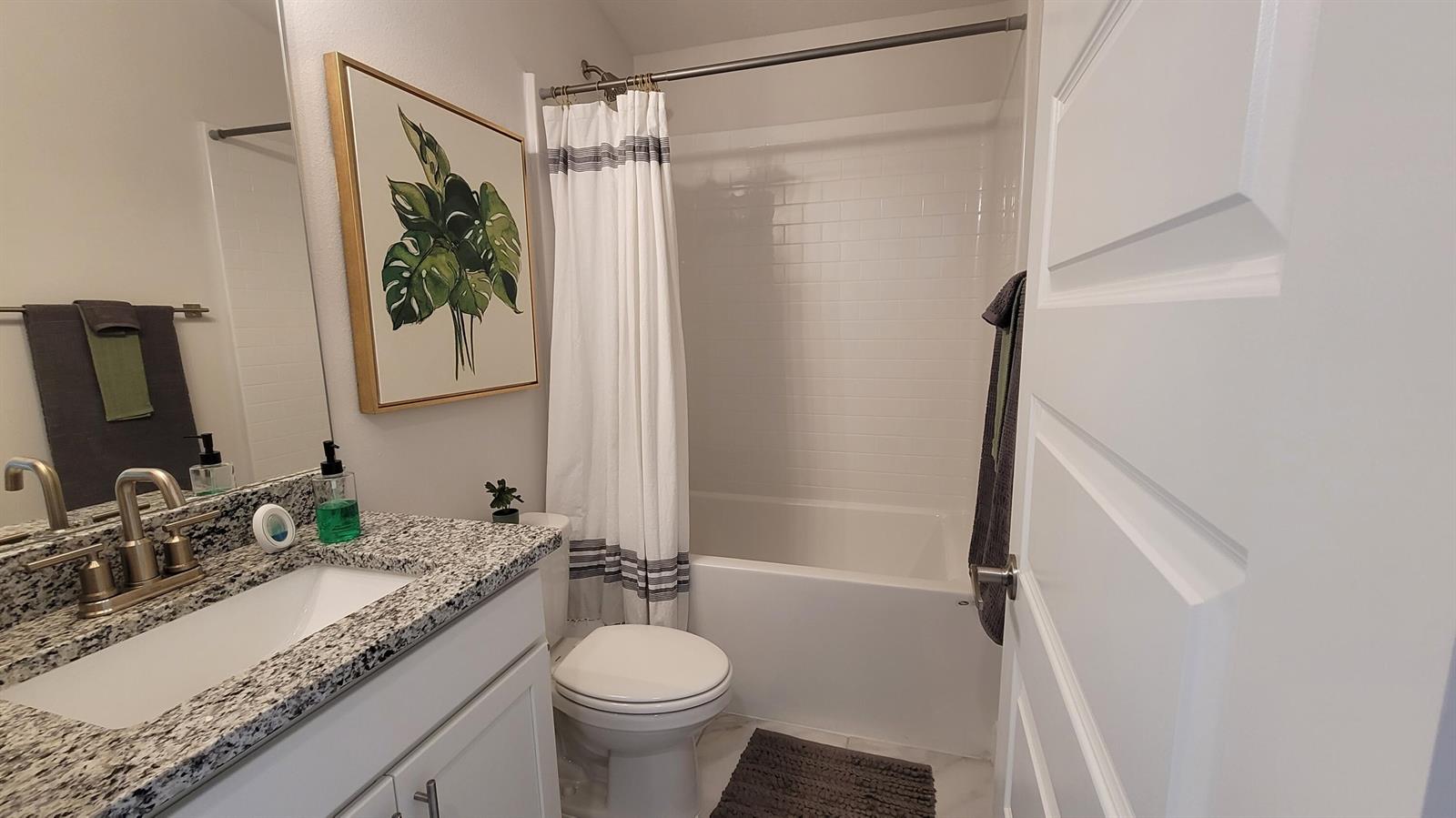 A bathroom features a granite vanity, white cabinets, a toilet, and a shower-tub combination — 8820 Waterstone Boulevard, Fort Pierce FL 34951, FORT PIERCE, FL