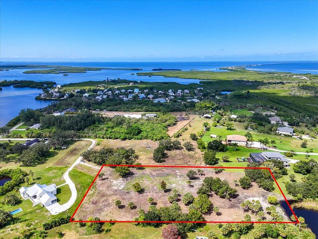 An aerial view shows a rectangular vacant lot outlined in red near a coastal residential area — 107 TILLETT PLACE, TERRA CEIA, FL