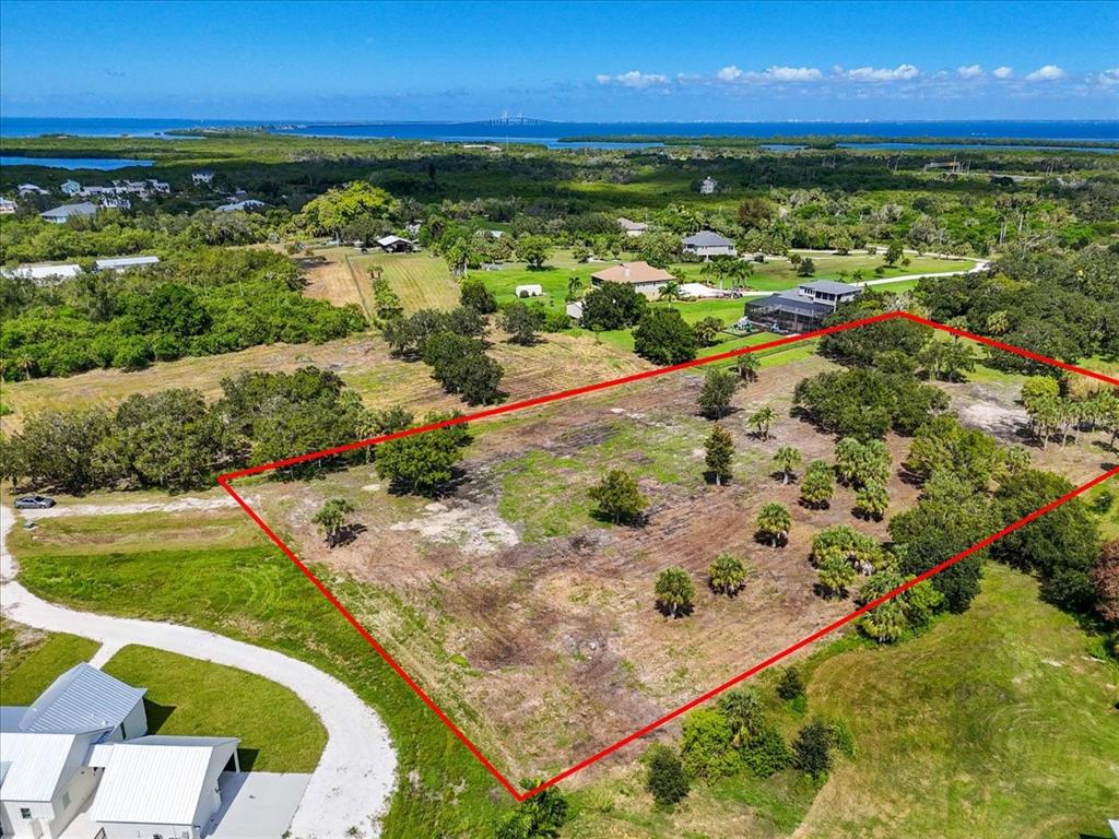 An aerial view shows a large, rectangular vacant lot outlined in red near residential homes — 107 TILLETT PLACE, TERRA CEIA, FL