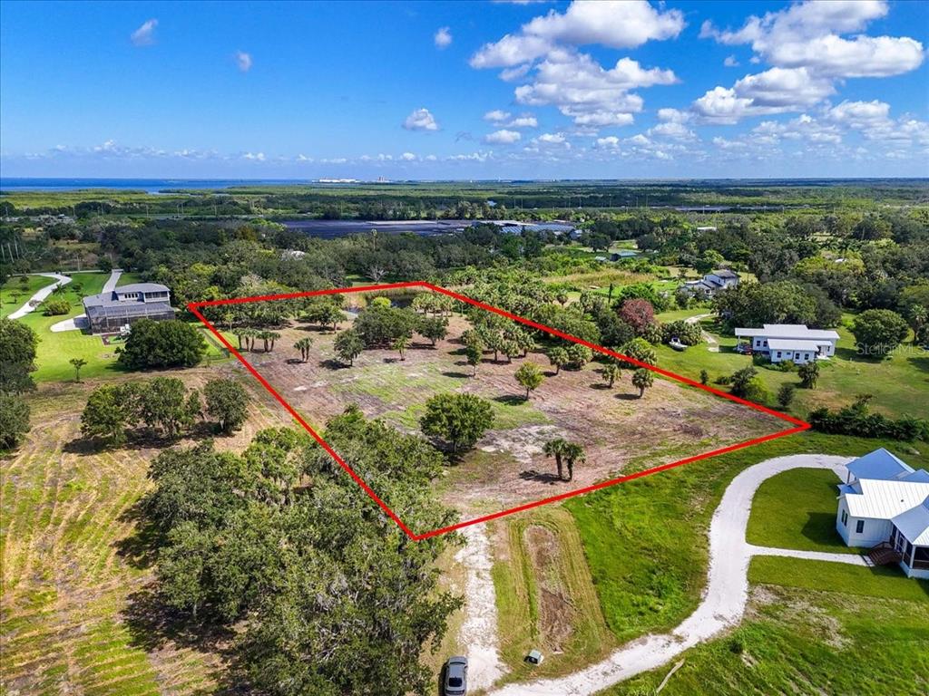 An aerial view shows a large, rectangular plot of land outlined in red near houses — 107 TILLETT PLACE, TERRA CEIA, FL