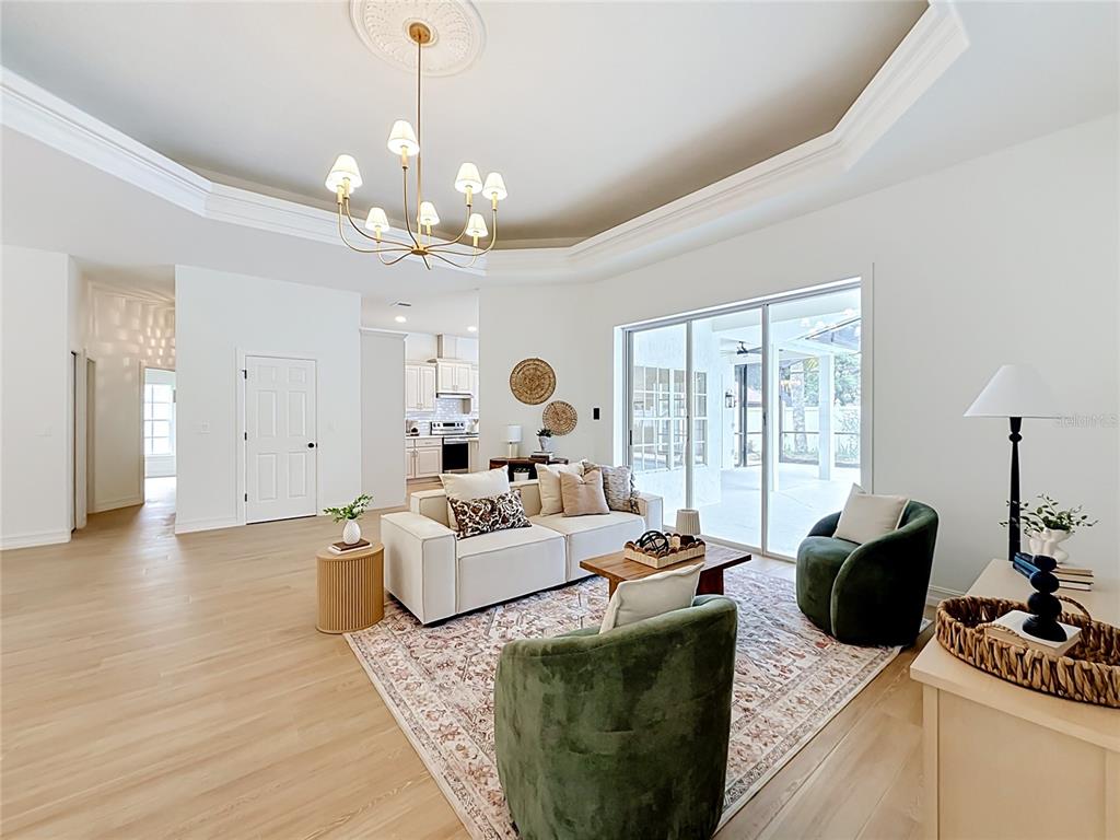 A living room features a tray ceiling, light wood floors, and two green velvet armchairs — 34239 WOODRIDGE LANE, EUSTIS, FL