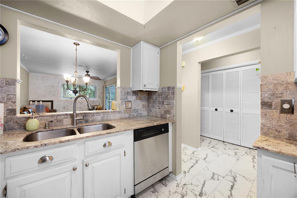 A kitchen with white cabinets, granite countertops, a stainless steel dishwasher, and marble-look tile flooring — 1001 PINE ISLE LANE UNIT 1001, NAPLES, FL