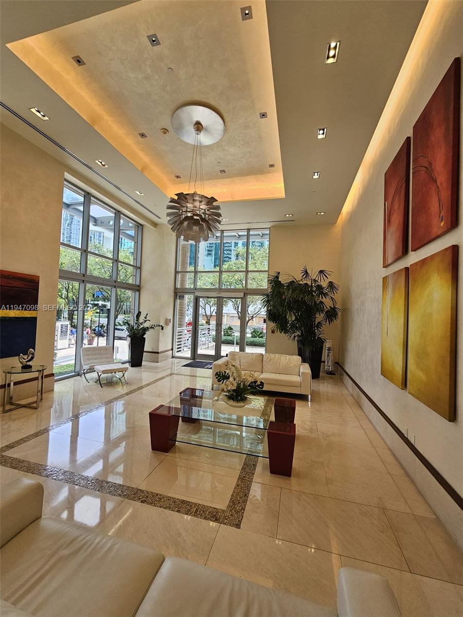A modern lobby features high ceilings, floor-to-ceiling windows, polished tile floors, and contemporary furniture — 1060 Brickell Ave # 1917, Miami FL 33131, MIAMI, FL
