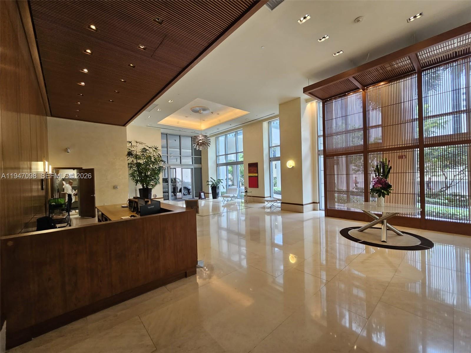 A spacious lobby features a wooden reception desk, high ceilings, and large glass windows — 1060 Brickell Ave # 1917, Miami FL 33131, MIAMI, FL