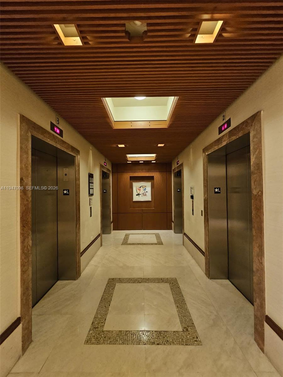 A hallway features two stainless steel elevators, marble flooring, and a slatted wood ceiling — 1060 Brickell Ave # 1917, Miami FL 33131, MIAMI, FL