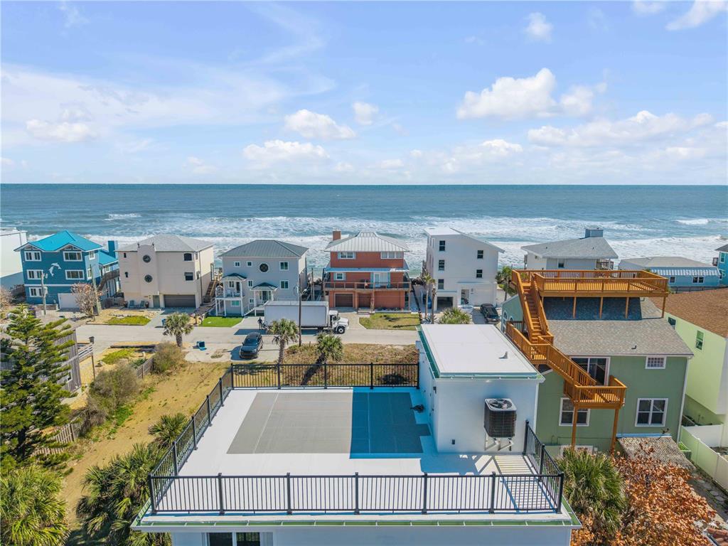 An aerial view shows a flat roof with a railing overlooking a beach and ocean — 6857 TURTLEMOUND ROAD, NEW SMYRNA BEACH, FL
