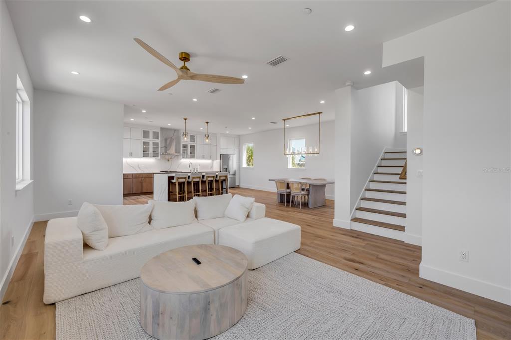 An open-concept living room, dining area, and kitchen feature white walls and light wood flooring — 6857 TURTLEMOUND ROAD, NEW SMYRNA BEACH, FL