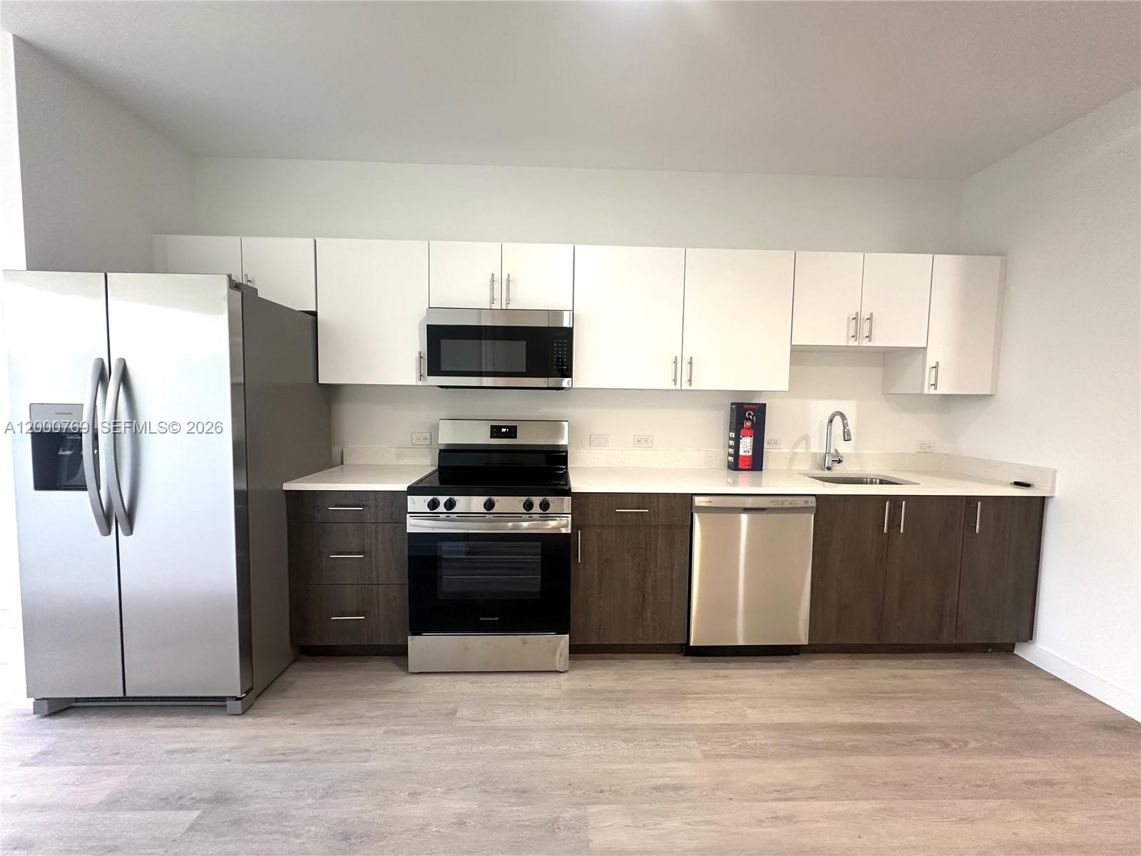 A modern kitchen features stainless steel appliances, white upper cabinets, and dark wood lower cabinets — 20 NE 19th Ave # 304, Pompano Beach FL 33060, POMPANO BEACH, FL