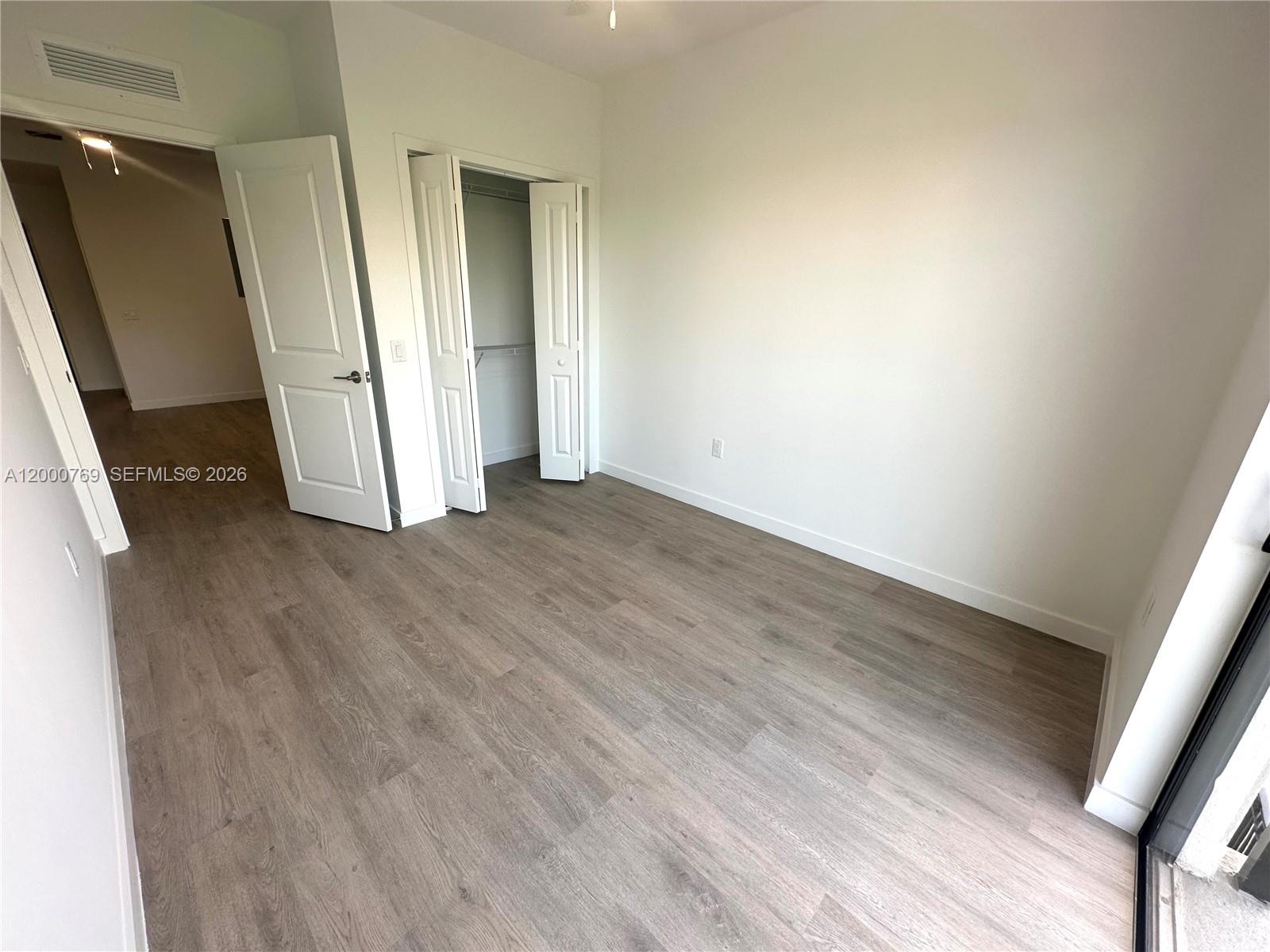An empty bedroom features light wood-look flooring, white walls, and a closet with bifold doors — 20 NE 19th Ave # 304, Pompano Beach FL 33060, POMPANO BEACH, FL