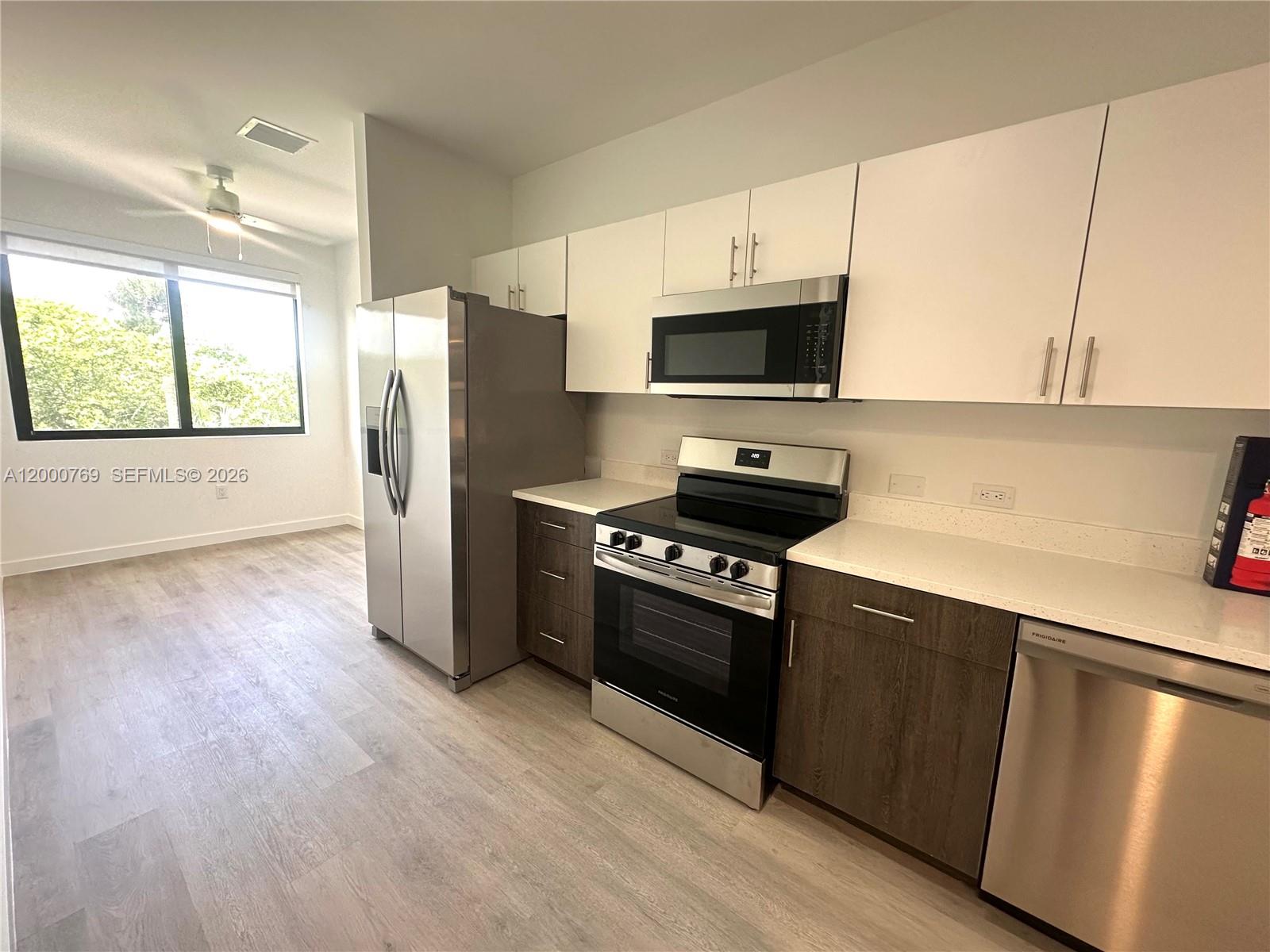 A kitchen features stainless steel appliances, white upper cabinets, and dark wood lower cabinets — 20 NE 19th Ave # 304, Pompano Beach FL 33060, POMPANO BEACH, FL