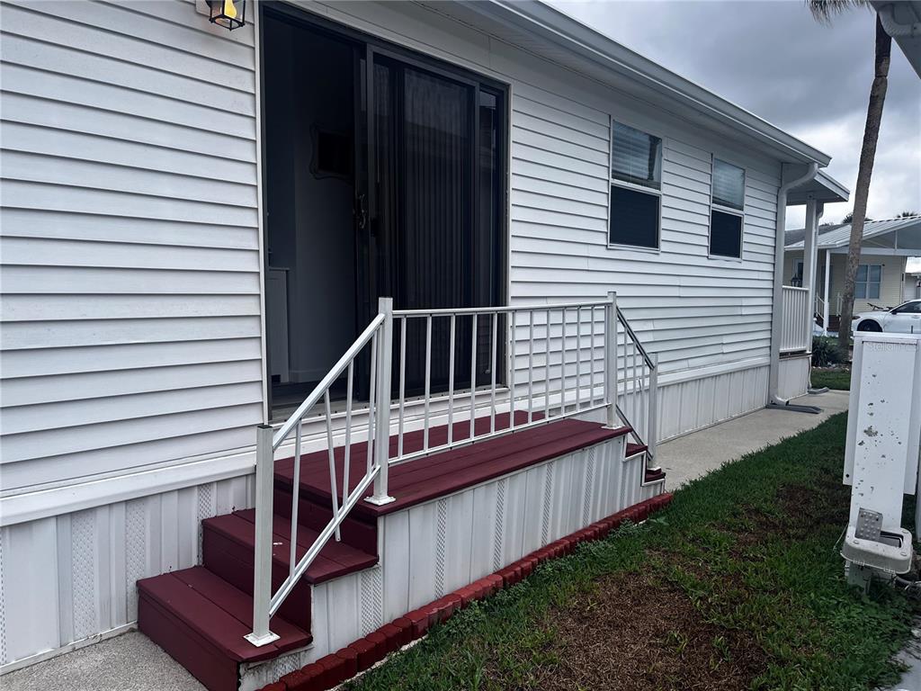 A white mobile home exterior features a red wooden staircase with a white metal railing — 9000 US HIGHWAY 192 UNIT 317, CLERMONT, FL