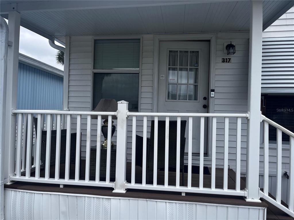 A white mobile home features a covered front porch with a white railing and door — 9000 US HIGHWAY 192 UNIT 317, CLERMONT, FL
