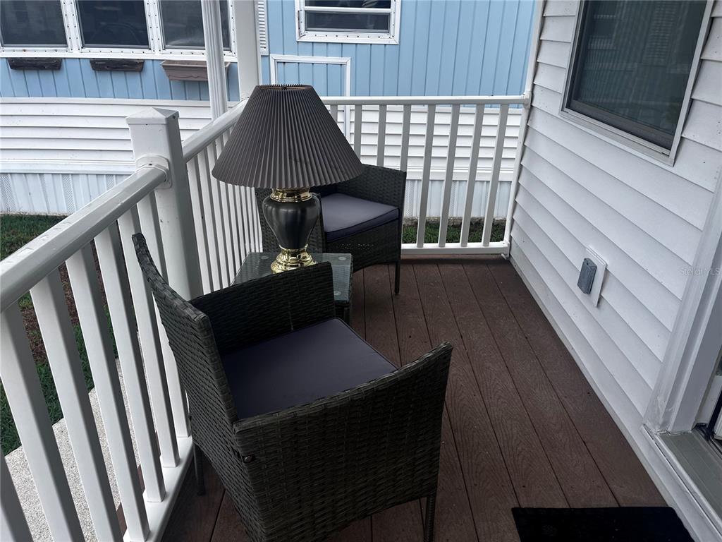 A small porch features two wicker chairs, a side table, and a lamp — 9000 US HIGHWAY 192 UNIT 317, CLERMONT, FL