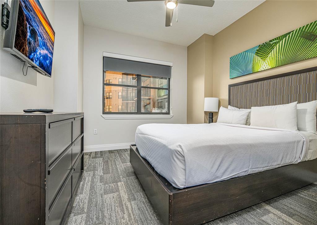 A bedroom features a bed with a dark headboard, a dresser, and a wall-mounted television — 14501 GROVE RESORT AVENUE UNIT 2534, WINTER GARDEN, FL