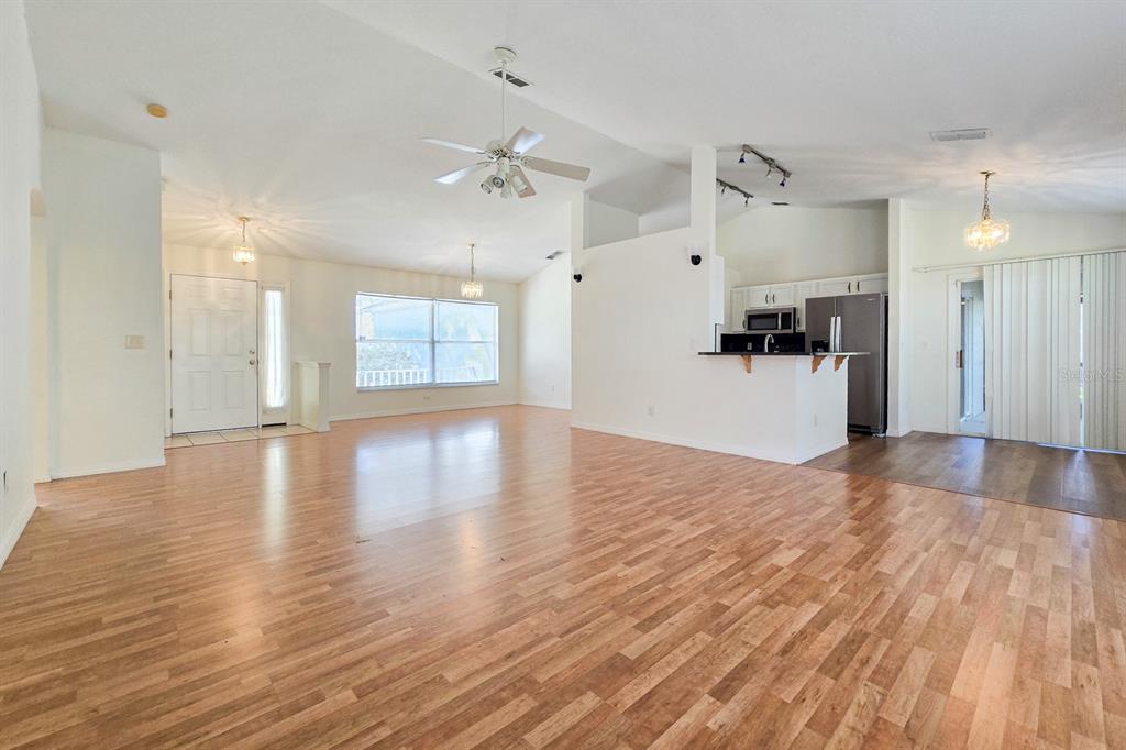 An open-concept living area with wood-look flooring, a kitchen island, and a ceiling fan — 10417 LAKE HASSON CIRCLE, CLERMONT, FL
