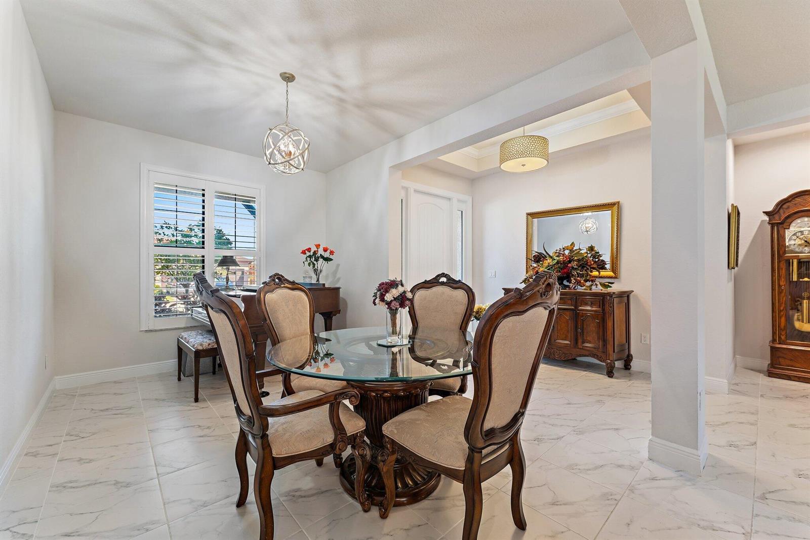 A dining room features a glass-topped table, four upholstered chairs, and white marble-look tile flooring — 6291 Arcadia Square, Vero Beach FL 32966, VERO BEACH, FL