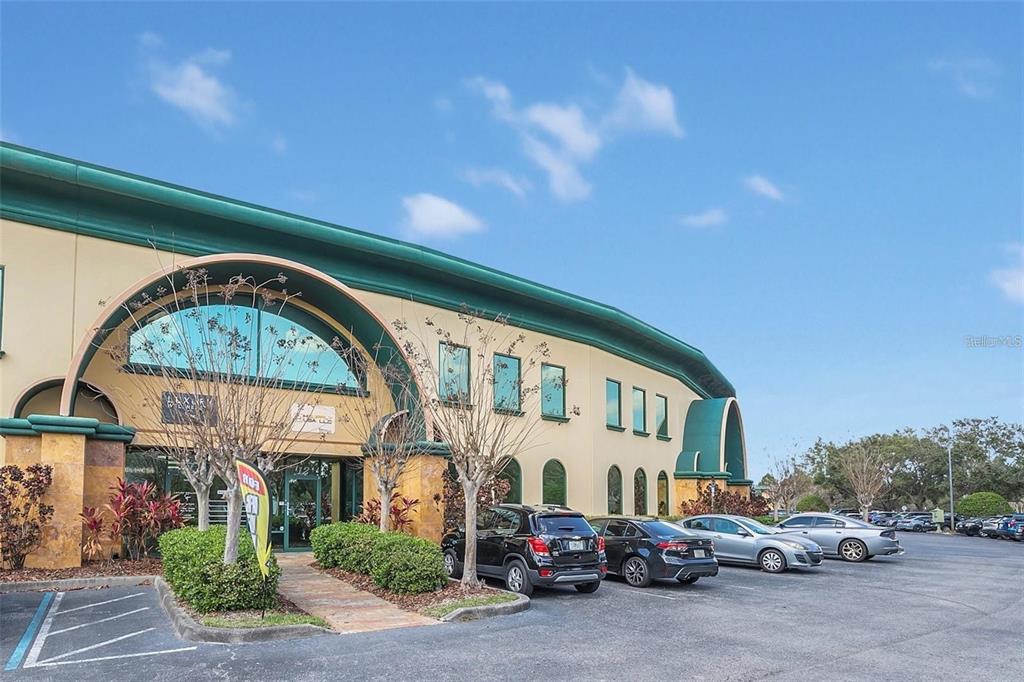 A low-angle exterior view of a commercial building with a curved roof and parking lot — 6881 KINGSPOINTE PARKWAY UNIT 11, ORLANDO, FL